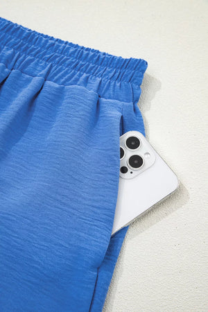 Blue textured drawstring shorts with elastic waistband and side pocket holding a phone.