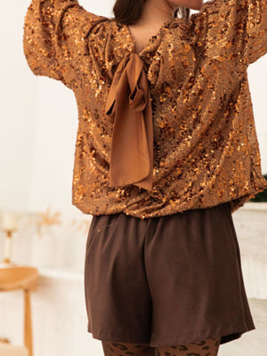 Dazzling sequin blouse in ochre with a tie-back detail and long sleeves.