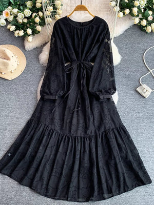 Black embroidered tie-waist midi dress with sheer sleeves and tiered skirt.