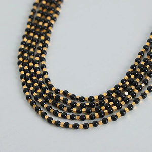 Black onyx and gold bead necklace with multiple strands.