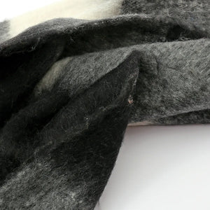 Checked plaid fluffy scarf in black and grey with white accents and fringe detail.