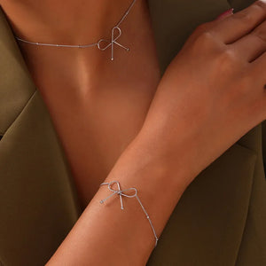 Silver delicate bow silhouette bracelet with beaded chain detail.