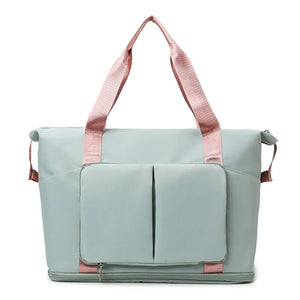 Sage green foldable travel tote with pink straps and two exterior pockets.