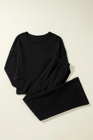 Black textured ribbed loungewear set with crewneck long sleeve top and wide leg pants.