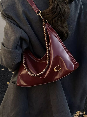 Chic crescent shoulder bag in glossy brown with gold chain strap and hardware.