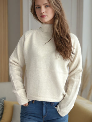 Relaxed cream turtleneck knit sweater with raglan sleeves and ribbed cuffs.