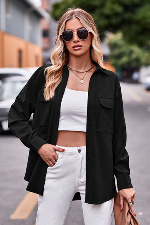 Black oversized utility shirt with chest pockets and button front, styled with white jeans.