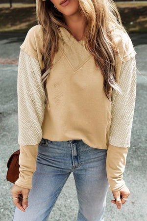 Tan and cream colorblock hoodie with textured sleeves and v-neck.