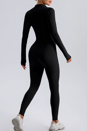 Black zip-front bodycon jumpsuit with long sleeves and thumbholes, worn with sneakers