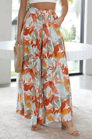 Botanical print palazzo trousers with paperbag waist and wide legs in orange, green, and aqua.