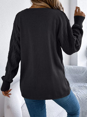 Black acrylic openwork cable knit cardigan with long sleeves.