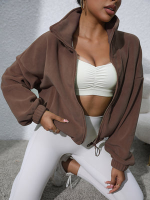Coffee brown fleece cropped jacket with funnel neck and zipper closure, styled with white athletic wear.