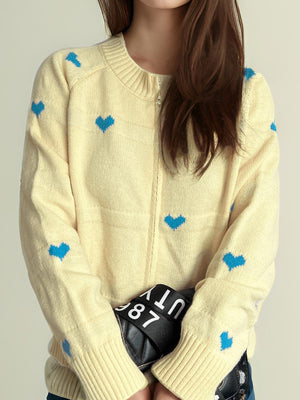 Pastel yellow zip-through knit cardigan with blue heart appliqué and ribbed cuffs.
