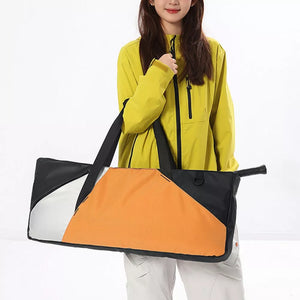 Modern color block travel bag in orange and black with white accents, featuring dual straps.