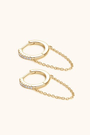 Gold dangling chain pavé huggie earrings with delicate cubic zirconia stones.