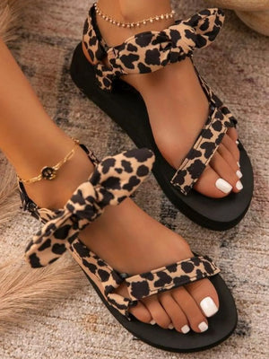 Leopard print flat sandals with bow detail and ankle strap.