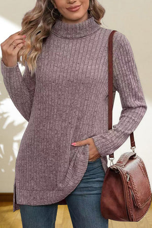 Ribbed knit turtleneck tunic top in lavender with side slits, styled with jeans and a crossbody bag.