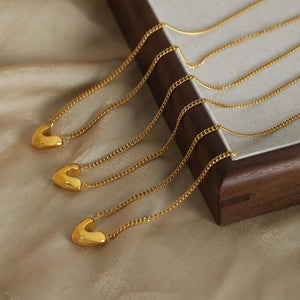 Gold heart charm necklaces with delicate curb chains.