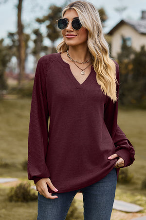 Burgundy waffle knit raglan v-neck top with textured sleeves.