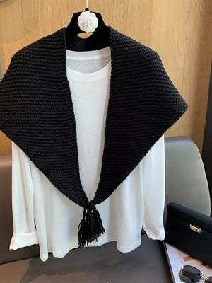Black textured knit scarf with tassels, styled over a white long-sleeve shirt.