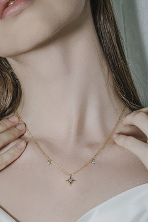 Gold celestial compass moissanite pendant necklace with dainty blue stones.