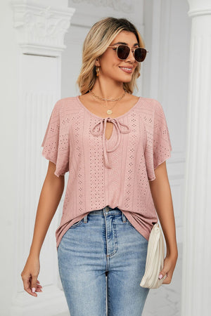 Pink eyelet tie-neck blouse with flutter sleeves and a V-neck.