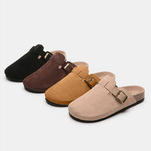 Suede clog slides with cork sole and buckle detail in black, chocolate, caramel, and beige.