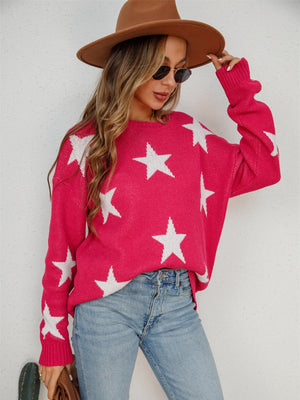 Pink crewneck sweater with white stars, long sleeves, and ribbed cuffs.