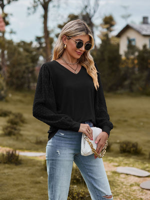 Black V-neck blouse with Swiss dot puff sleeves and cinched cuffs.
