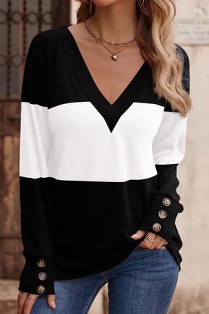 Black and white colorblock V-neck knit top with button cuffs.
