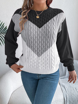 Chevron cable knit sweater with contrast black, gray, and white panels.