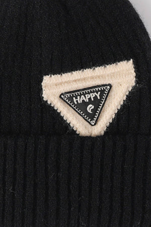Black ribbed acrylic beanie with a cream patch and a black triangle patch with "HAPPY" text.