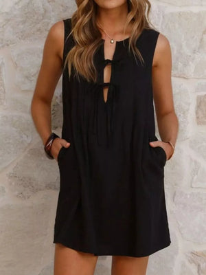 Black tie-front mini dress with pockets and a keyhole neckline.