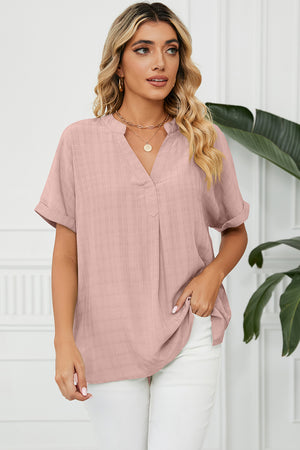 Blush pink blouse with rolled sleeves and a subtle plaid texture, featuring a V-neck and gathered back yoke.