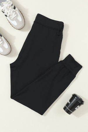 Black slim-fit joggers with drawstring waist and cuffed ankles.