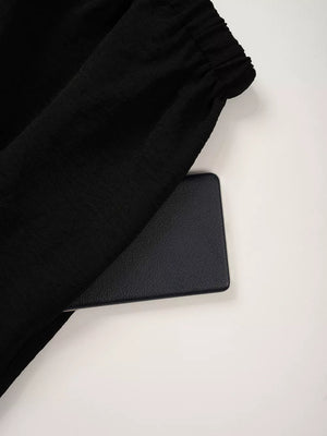 Black maternity pants with textured fabric and elastic waistband detail.