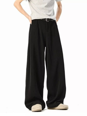 Men's black wide-leg track pants with a belt and light-colored shoes.