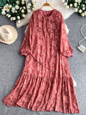 Rust embroidered tie-waist dress with tiered hem and balloon sleeves.
