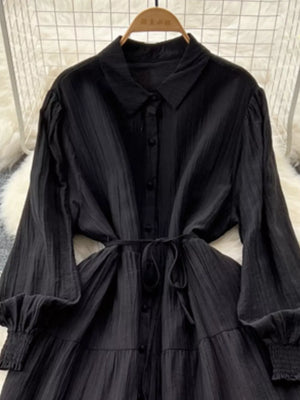 Black textured tiered long sleeve dress with button-down front and tie waist.