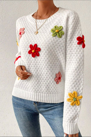 White knit sweater with crochet floral embellishments and diamond pattern.