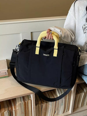 Black nylon travel duffel bag with yellow padded handles and adjustable strap