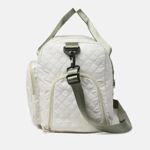 White quilted duffel bag with olive green strap and accents, side zip pockets.