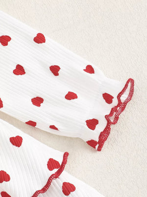 White cotton baby dress with red hearts and ruffled trim.