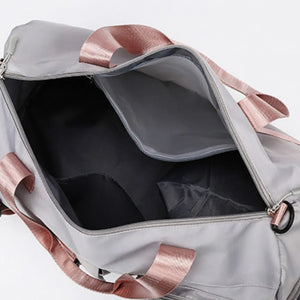 Gray gym duffel bag with dusty pink straps and interior pockets.