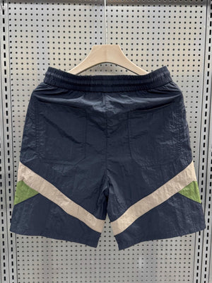 Men's shorts in dark blue with beige and green color block accents and elastic waistband.