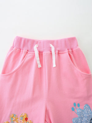 Pink cotton toddler pants with elastic waist, drawstring, and embroidered flower details.