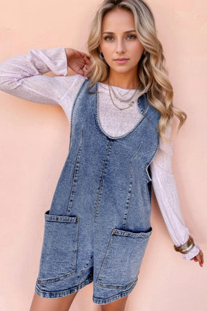 Acid wash denim romper with patch pockets and a scoop neckline.