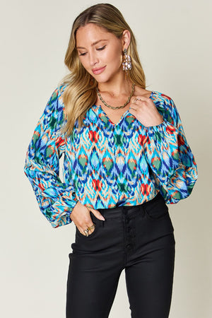 Prismatic ikat blouse in green and blue with voluminous sleeves and v-neck.