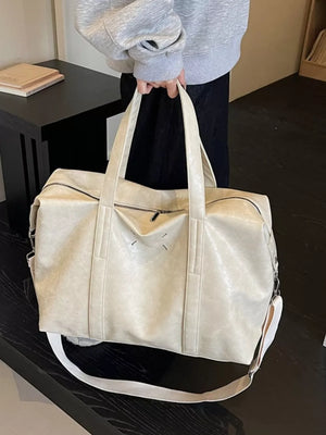 Cream white distressed vintage leather travel bag with top handles and crossbody strap.