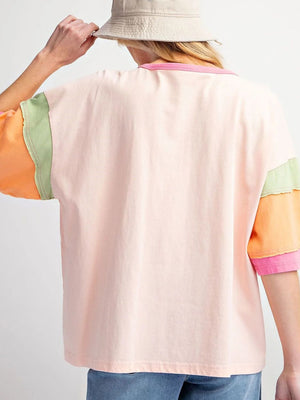 Colorblock floral t-shirt in watermelon pink with green and orange sleeves and raw hem detail.